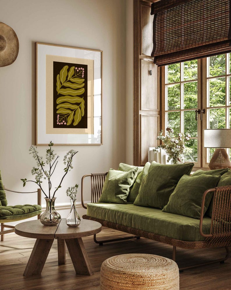 Pu&ograve; includere: Una stampa botanica incorniciata con foglie verde oliva e grappoli di bacche rosa su sfondo scuro. L'opera d'arte &egrave; in una stanza con un divano verde, mobili in legno e una tenda a rullo in tessuto. La stanza &egrave; decorata in toni neutri.