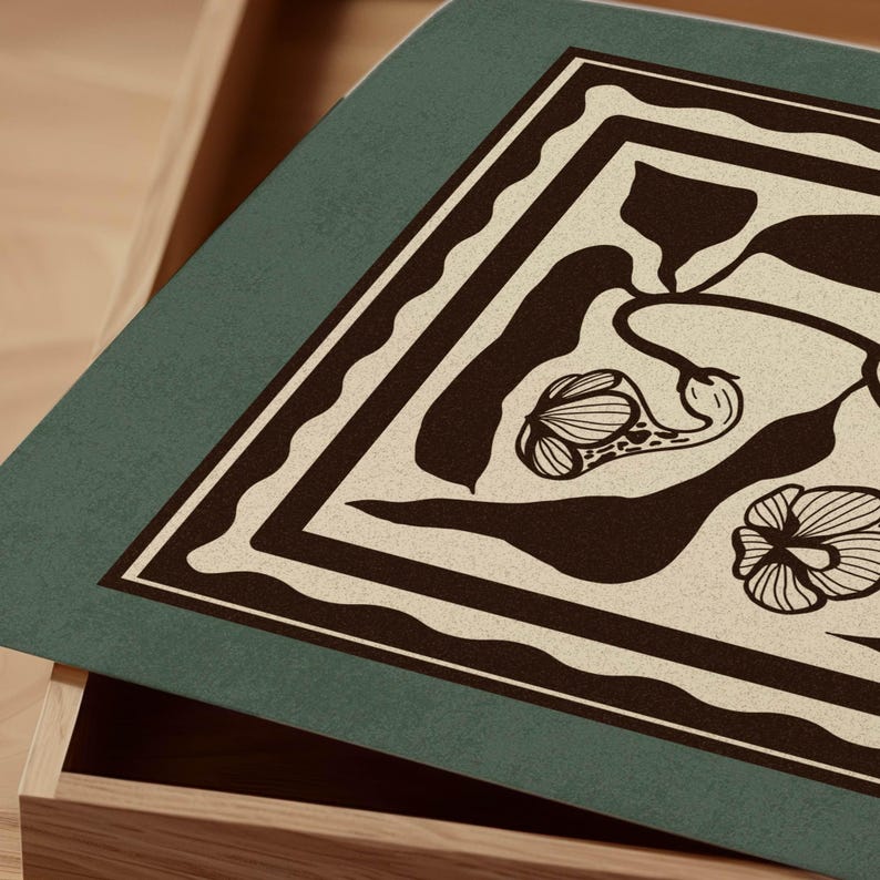 Op de afbeelding: Een rechthoekige, teal-gekleurde decoratieve mat met een beige bloemenontwerp en een donkerbruine rand. De mat bevindt zich gedeeltelijk in een houten lade, waardoor de textuur en het patroon worden benadrukt. Het bloemenontwerp omvat gestileerde bloem- en bladvormen.