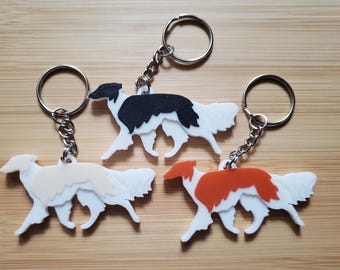 以下が含まれることがあります： ボルゾイ犬のシルエットがデザインされた3つのキーホルダー。黒と白、クリームと白、オレンジと白の犬の形をしたチャームがそれぞれ付いています。各キーホルダーには、銀色の金属製リングと短いチェーンが付いています。
