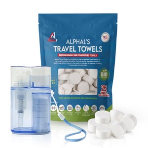 May include: A blue plastic dispenser with 25 white compressed travel towels in a clear plastic bag. The bag has a label that says "ALPHA1'S TRAVEL TOWELS" and "BIODEGRADABLE MINI COMPRESSED TOWELS". The label also says "100% VISCOSE, NON-WOVEN AND BIODEGRADABLE".