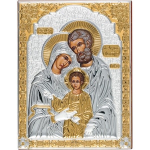Puede incluir: Un icono plateado y dorado que representa a la Sagrada Familia. El icono presenta una imagen detallada de María, José y el niño Jesús. El icono está enmarcado en un borde dorado y plateado con intrincados diseños florales.