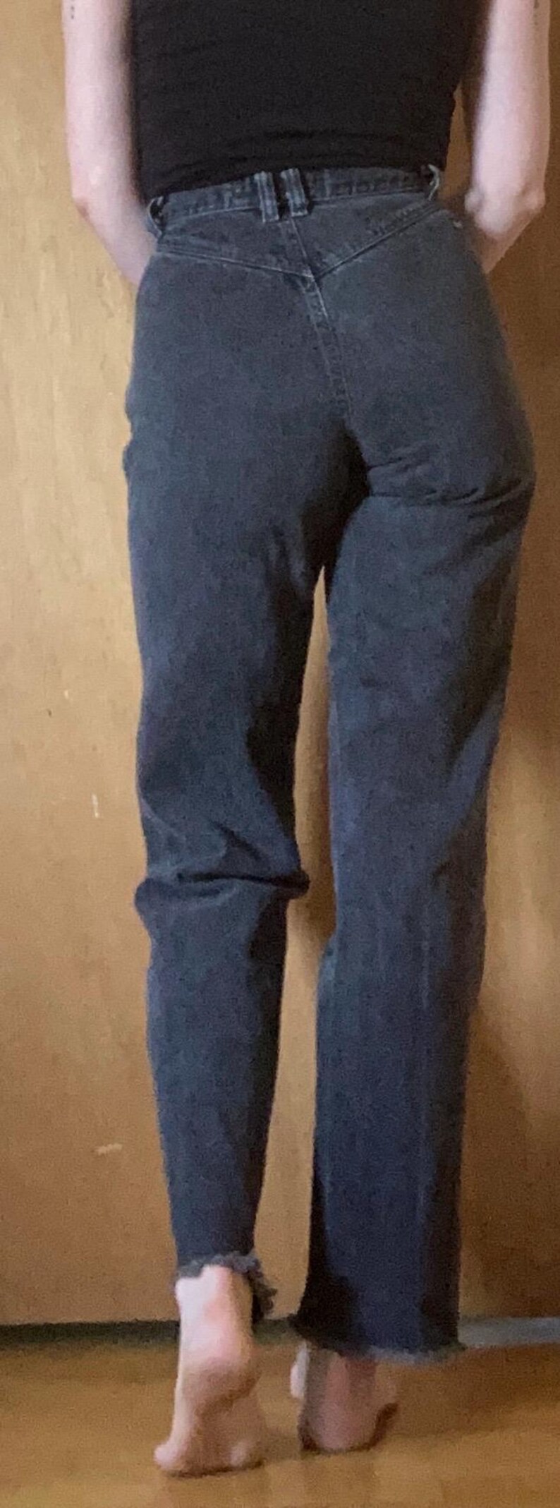 Puede incluir: Vaqueros negros de tiro alto con canes&uacute; trasero en forma de V, trabillas para cintur&oacute;n y bajo deshilachado en los tobillos. Los pantalones presentan un corte recto y una construcci&oacute;n cl&aacute;sica de cinco bolsillos en tejido denim negro lavado.
