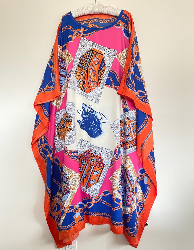 May include: A long, flowing, pink, orange, and blue patterned kaftan with a chain link design. The kaftan has a round neckline and is made of a silky fabric.