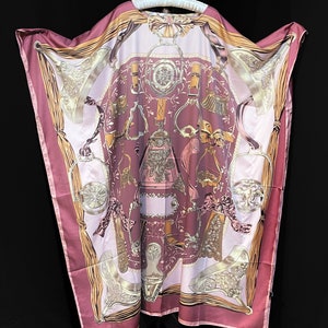 May include: A pink silk robe with a gold and white print of equestrian themed designs. The robe has a wide, flowing silhouette and a relaxed fit.