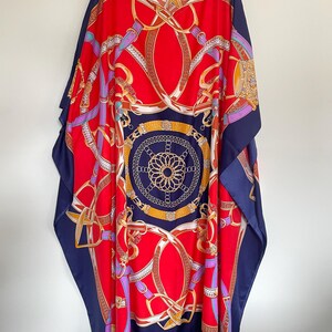 May include: A red and navy blue kaftan with a gold and white chain print. The kaftan has a V-neck and a loose fit.