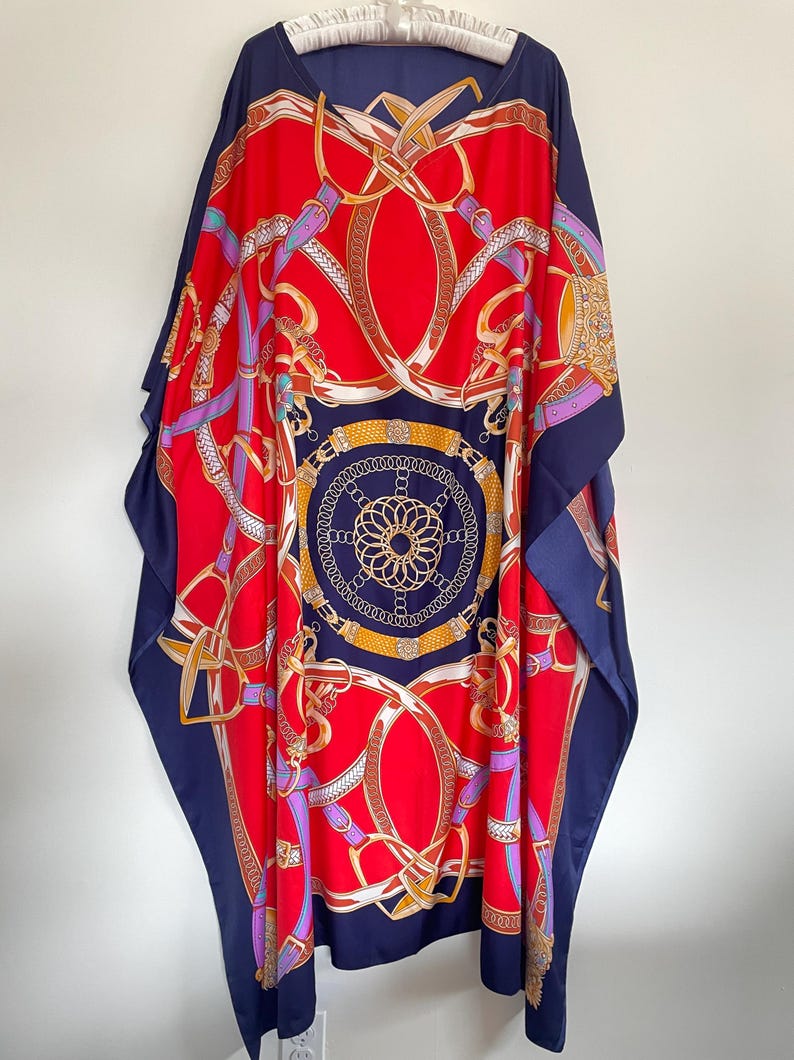May include: A red and navy blue kaftan with a gold and white chain print. The kaftan has a V-neck and a loose fit.