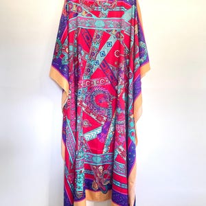 May include: A long, flowing, pink and purple kaftan with a colorful geometric pattern of belts, buckles, and other designs. The kaftan has a round neckline and a relaxed fit.