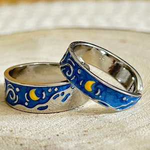 Może przedstawiać: Dwa srebrne pierścionki z niebiesko-żółtym wzorem emaliowanym inspirowanym obrazem Gwiezdnej nocy Vincenta van Gogha.