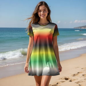 Peut inclure: Une robe à manches courtes avec un dégradé de couleurs vives : jaune, rouge, vert et gris. La robe est portée sur une plage de sable avec l'océan en arrière-plan. Elle a un col rond et une jupe évasée.