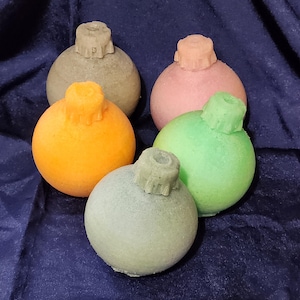 May include: Five Christmas ornaments in various colors, including green, orange, pink, and gray. The ornaments are round and have a textured surface.