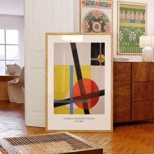 May include: A framed abstract art print with geometric shapes in black, white, yellow, blue, and red. The print is titled "László Moholy-Nagy, A sz 2 (1927)".