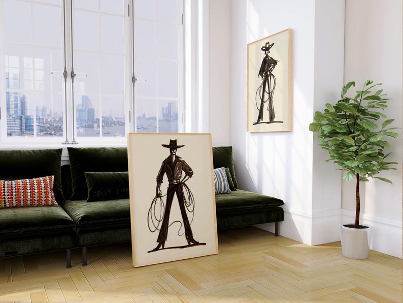 Pu&ograve; includere: Due stampe artistiche incorniciate raffiguranti un bozzetto in bianco e nero di un cowboy con un lazo. Una stampa &egrave; appoggiata a un muro, l'altra &egrave; appesa. La stanza ha un divano in velluto verde, una pianta in vaso e una vista sulla citt&agrave; attraverso una grande finestra.