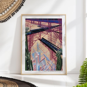 May include: Framed art print of an architectural fantasy by Yakov Chernikhov. The artwork features a complex, multi-layered construction with red, blue, and green elements. The print is in a wooden frame and is displayed on a white wall.