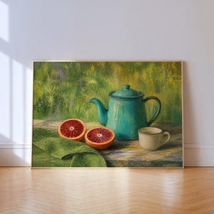 Puede incluir: Un cuadro al óleo enmarcado que muestra una tetera color cerceta, una pequeña taza beige y dos mitades de naranja sanguina sobre una superficie de madera. Un paño verde se extiende junto a la fruta, sobre un fondo verde texturizado e impresionista.