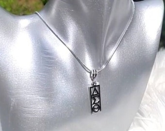 Op de afbeelding: Een zilveren ketting met een hanger met een verticale balk met de Griekse letters Delta, Sigma en Theta.