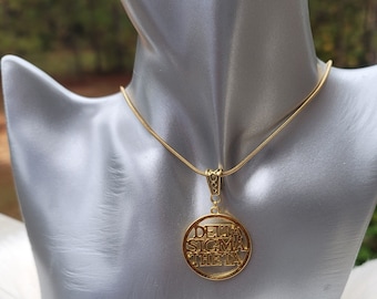 Op de afbeelding: Een gouden ketting met een ronde hanger waarop "Delta Sigma Theta" in gouden letters staat.