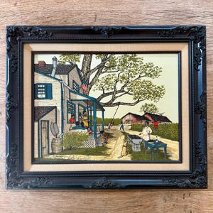Peut inclure: Une peinture encadr&eacute;e repr&eacute;sentant une sc&egrave;ne de campagne avec une maison blanche, un grand arbre et des gens rassembl&eacute;s autour d'une table. La maison a un porche avec une balan&ccedil;oire et un drapeau accroch&eacute; au toit. Les gens sont habill&eacute;s en v&ecirc;tements d&eacute;contract&eacute;s et profitent du plein air. La peinture est r&eacute;alis&eacute;e dans un style r&eacute;aliste avec des couleurs vives.