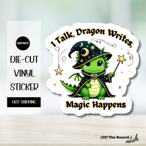 May include: A green dragon wearing a black wizard hat with a crescent moon and stars. The dragon is holding a wand with a star on top. The text "I Talk, Dragon Writes, Magic Happens" is written around the dragon.