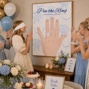 Op de afbeelding: Een grote rechthoekige spelposter getiteld Pin the Ring Lori's Bridal Shower met een handillustratie met een ring, omringd door blauwe lijntekeningen van boeketten en sieraden, weergegeven in een gouden lijst voor een bruidsfeest.