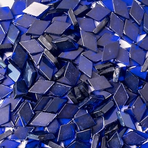 May include: A pile of small, dark blue diamond-shaped glass tiles. The tiles are scattered randomly and are all the same size and shape.