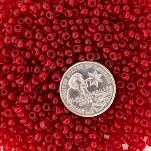 May include: A close-up image of a pile of small, red glass seed beads. A US quarter is included for scale.