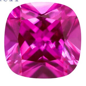 Puede incluir: Una gema rosa vibrante con un corte cojín y un diseño facetado. La gema está cortada para crear un efecto brillante y brillante.