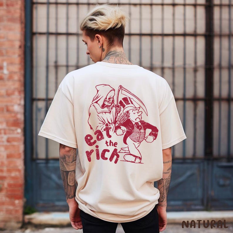 May include: A cream colored t-shirt with a red graphic print of a skeleton holding a scythe and a man in a top hat running away. The text "eat the rich" is printed below the graphic.