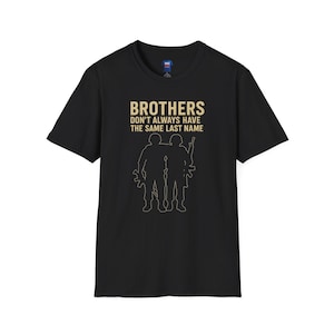 May include: Black t-shirt with the text "BROTHERS DON'T ALWAYS HAVE THE SAME LAST NAME" in gold lettering. Below the text is a gold outline of two soldiers with weapons.