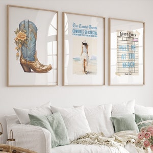 Puede incluir: Tres impresiones enmarcadas en una pared blanca sobre un sofá blanco. La impresión de la izquierda presenta una bota vaquera azul y dorada con una flor amarilla. La impresión del medio presenta a una mujer con un vestido blanco caminando por una playa con el texto "The Coastal Gazette COWGIRLS GO COASTAL A FRESH FUSION OF WESTERN AND BEACH VIBES". La impresión de la derecha presenta un cheque de huésped vintage con el texto "GUEST CHECK MEET ME AT THE BEACH Thank You!"