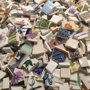 Puede incluir: Una colección de piezas de azulejos de cerámica coloridos en varias formas y tamaños. Los azulejos presentan patrones florales, diseños geométricos y arte abstracto. Algunos azulejos son blancos con acentos azules, mientras que otros son multicolores.