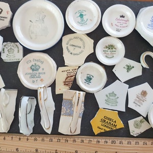 May include: A collection of broken pieces of vintage china teacups and saucers. The pieces are arranged on a black surface with a ruler for scale. The pieces feature various logos and designs, including "Romance", "Old English", "Johnson Bros", "Royal Albert", "Myott Son", "Colclough", "Gisela Graham", "Paragon", "Duchess", "F.C. Emery", "Emma Bridgewater", "Adam", and "Myott Son".