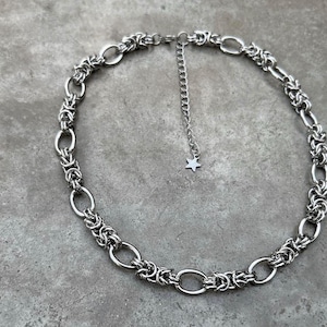 May include: A silver chain necklace with a star charm. The chain is made of interlocking oval links.
