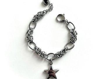 Op de afbeelding: Een zilveren armband met een stervormige hanger. De armband is gemaakt van een ketting met een hartvormige sluiting.