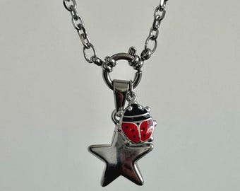 May include: A silver chain necklace with a silver star charm and a red ladybug charm.