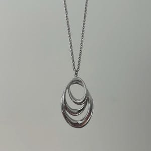 May include: A silver necklace with a pendant featuring three interlocking oval shapes.
