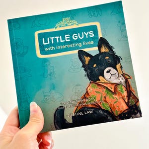 May include: A teal blue book cover with a cartoon dog wearing a floral shirt. The title is "Little Guys with interesting lives" and the subtitle is "Dog Coloring Book 30 pages of good dogs being good". The author is Justine Law.