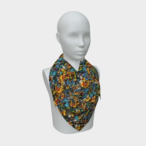 May include: A patterned scarf in shades of blue, yellow, red, and black, displayed on a white mannequin. The scarf's design is abstract and artistic, with a mix of colors. The scarf is a square shape, and is draped around the mannequin's neck.