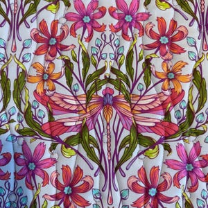 May include: Close-up of a floral pattern featuring stylized flowers and foliage in shades of pink, orange, green, and purple on a light blue background. The design includes symmetrical arrangements of flowers and leaves.