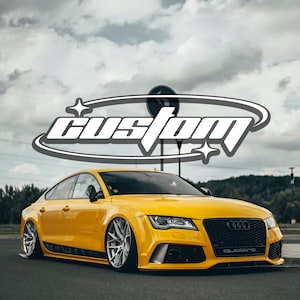 Puede incluir: Un sedán Audi de color amarillo brillante con suspensión rebajada y llantas plateadas de radios múltiples. La parrilla delantera presenta el logotipo de Audi y una insignia quattro. Superposición gráfica con la palabra custom en blanco.