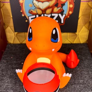 Può includere: Vaso da fiori Pokemon Charmander arancione e rosso con design Pokeball. Il vaso è in plastica e ha una piccola apertura in cima per piantare.