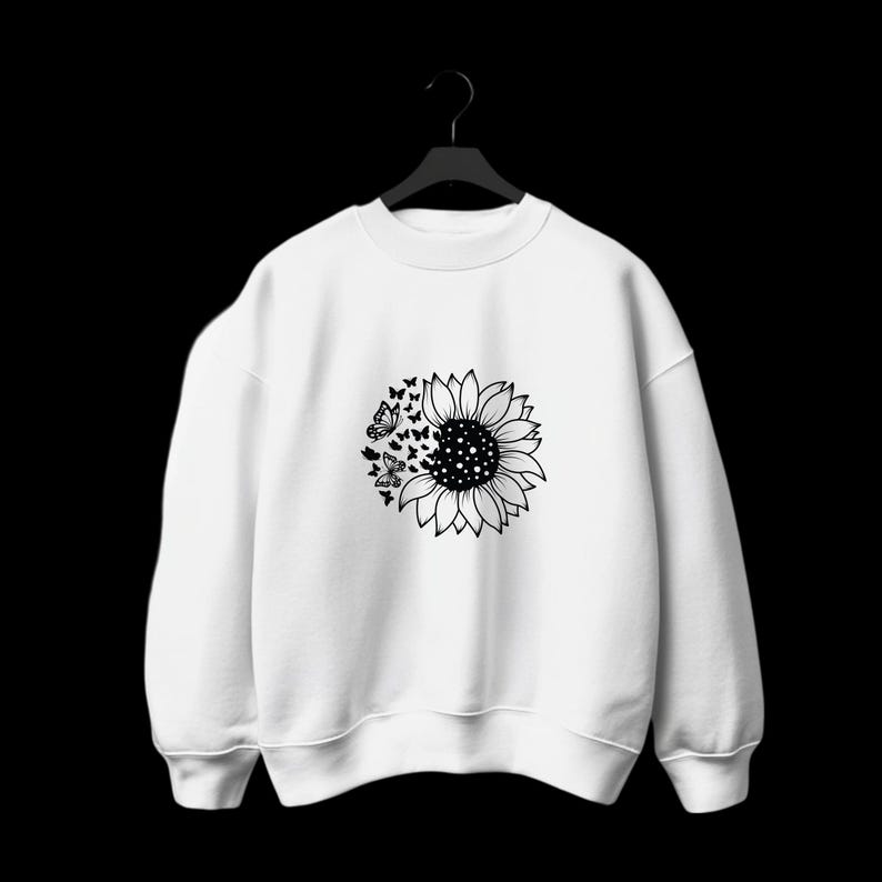 Puede incluir: Sudadera blanca con un gr&aacute;fico en blanco y negro de un girasol con mariposas volando.