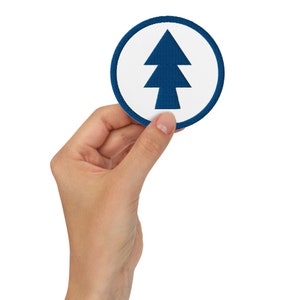 May include: A blue and white round patch with a blue stylised pine tree design.