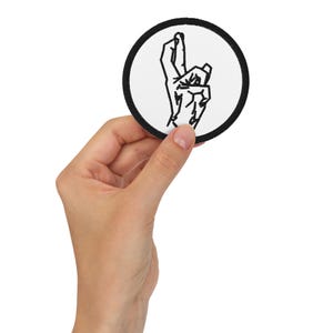May include: A black and white embroidered patch of a hand making the 'okay' sign, with the index finger and thumb touching, and the other fingers extended. The patch is circular and has a black border.