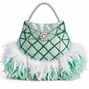Può includere: Una borsa in raso verde chiaro con un motivo a griglia di cristalli verde scuro, una spilla centrale a fiore in cristallo, una tracolla a catena argentata con perle bianche e una base rifinita con piume bianche e verde chiaro.