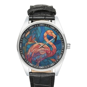 May include: A stainless steel wristwatch with a black leather band. The watch face features a colorful stained-glass design of a flamingo. The flamingo is depicted in shades of pink, orange, and purple against a blue background.
