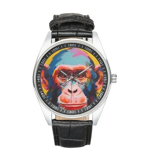 Peut inclure: Une montre-bracelet argent&eacute;e avec un bracelet en cuir noir. Le cadran de la montre pr&eacute;sente une peinture abstraite color&eacute;e d'un visage de singe.