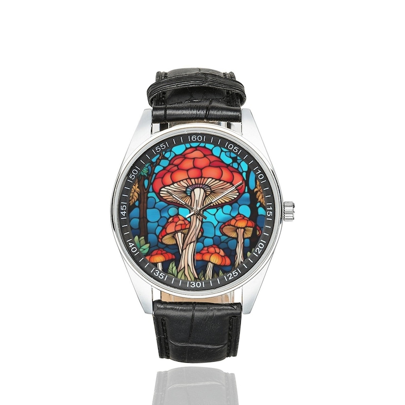 May include: A silver wristwatch with a black leather band features a colorful stained glass design of red mushrooms with blue and green accents. The watch face has white numbers and markings.