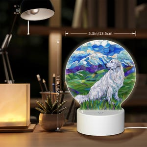 May include: A white dog sitting in a field with mountains in the background. The image is on a round, white, 3D printed night light with a 5.3 inch diameter and 7.1 inch height.