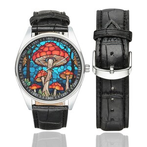 May include: A silver wristwatch with a black leather band. The watch face features a colorful stained glass design of mushrooms.