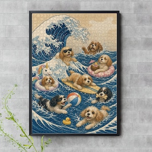 Op de afbeelding: Een ingelijste legpuzzel met een gestileerde illustratie van meerdere gouden en zwart-witte puppy's die in blauwe oceaangolven spelen. De scène bevat een grote golf, een surfplank, een eenhoorn-zwemband, een strandbal en een gele badeend.